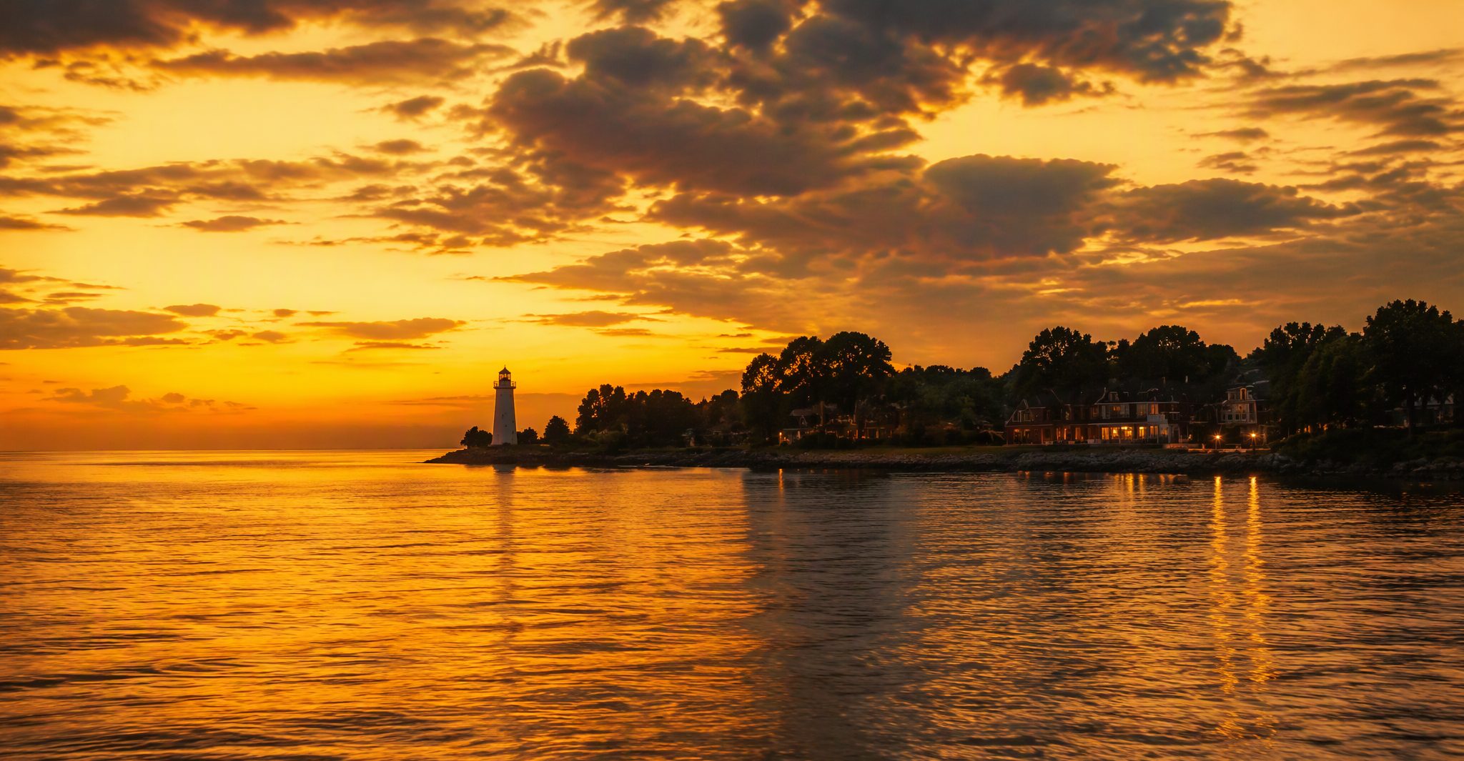Lake Erie shoreline and the Presque Isle lighthouse under a golden dusk sky